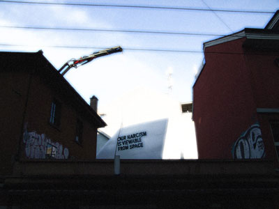 Tail fin with truism "our narcism is viewable from space" is placed to the terrasse of Perla-Mode