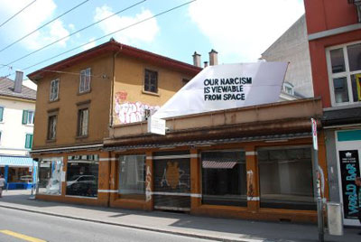 Tail fin with truism "our narcism is viewable from space" is placed to the terrasse of Perla-Mode